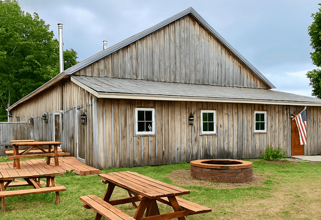 Rustic wooden building with picnic tables and fire pit on grassy lawn