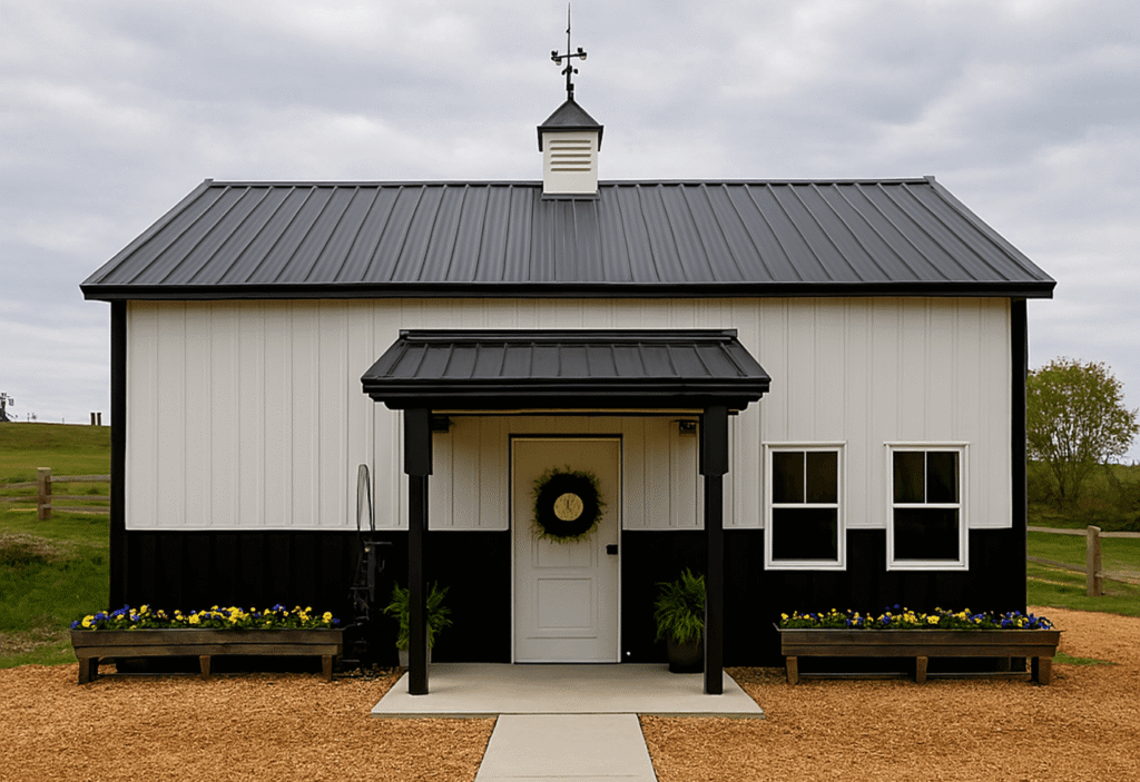 Modern barn-style building with black roof, white siding, and flower beds